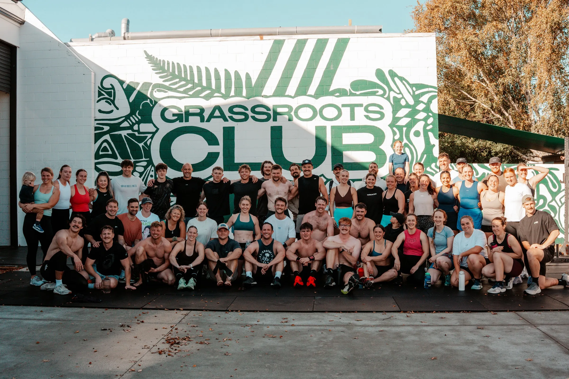 The whole Grassroots Club crew lined up under the big club mural.